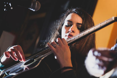 Low angle view of young woman playing guitar