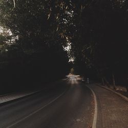 Road amidst trees against sky at night