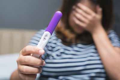 Midsection of woman holding pregnancy test equipment