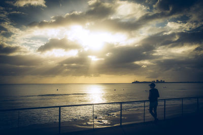 Silhouette people standing on beach against sky during sunset
