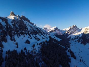 Scenic view of snowcapped mountains against blue sky