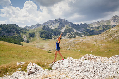 Side view of woman standing on rocks against landscape