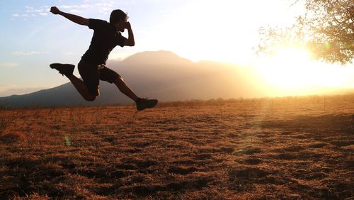 Full length of man jumping on mountain during sunset