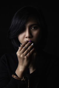 Portrait of young woman against black background