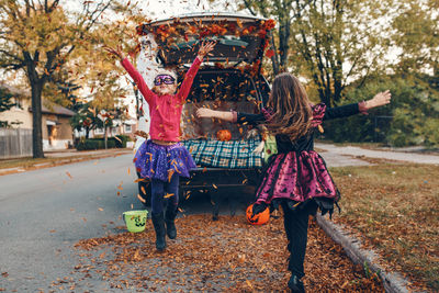 Full length of cute girls standing by car at road