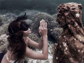 Rear view of woman on rock at sea