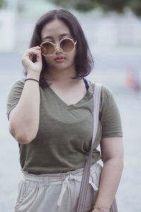 Portrait of young woman wearing sunglasses standing outdoors