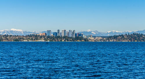 Scenic view of sea and buildings against clear blue sky