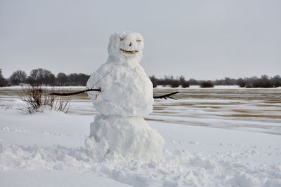 Snowman on the river bank 