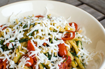 Close-up of pasta with cheese in bowl on wooden table