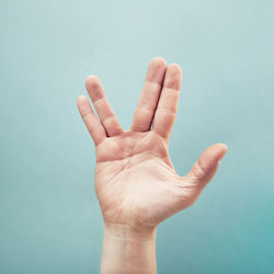 Cropped hand gesturing against turquoise background