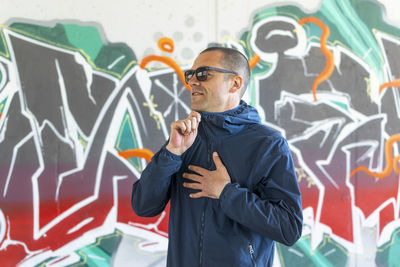 Full length of man standing against graffiti wall