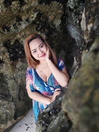 Portrait of a smiling young woman standing on rock