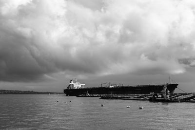 Boats in sea against cloudy sky