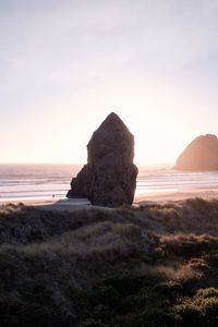 Rock formation on beach against sky during sunset