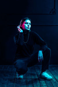 Portrait of young woman sitting on hardwood floor