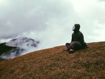 Woman wearing mask sitting on mountain