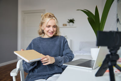 Portrait of young woman using laptop while sitting at home