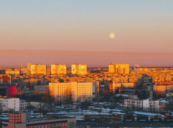 High angle view of buildings against sky with fool moon during sunset