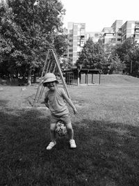 Portrait of cute girl holding ball while standing on grassy field at park