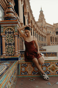 Side view of woman sitting on a building in seville. plaza de espana - spain square