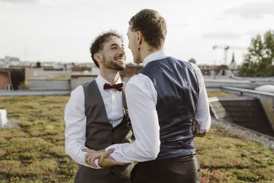 Romantic gay couple looking at each other while standing on rooftop