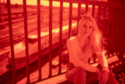 Portrait of young woman sitting by railing