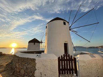 Lighthouse by sea against sky during sunset