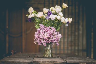 A bouquet of purple flowers in a glass vase on a wooden floor boards of old vintage. the home decor