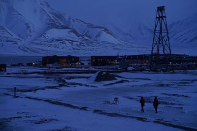 People on snow covered field against sky