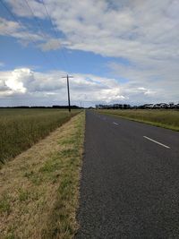 Road amidst field against sky