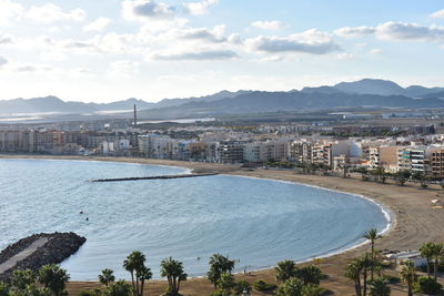 High angle view of city by sea against sky