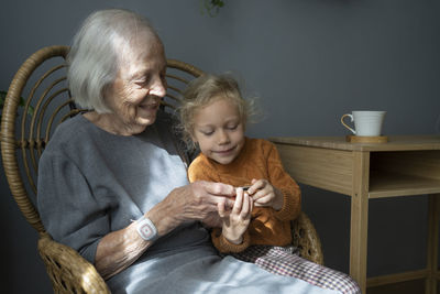 Happy grandmother with granddaughter looking at camera on chair