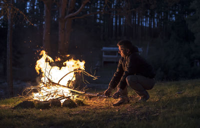 Man with campfire in forest during dusk