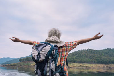 Rear view of man with arms outstretched against sky