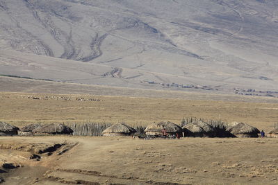 Thatched roof houses against mountains in village on sunny day