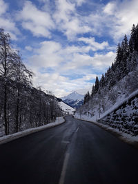 Road leading towards mountains against sky during winter