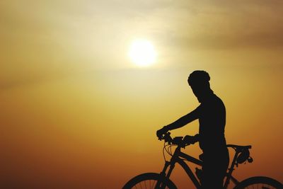 Silhouette man with bicycle against sky during sunset