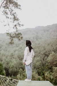 Side view of woman standing against mountain