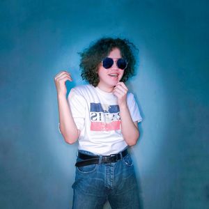 Portrait of young man wearing sunglasses standing against wall