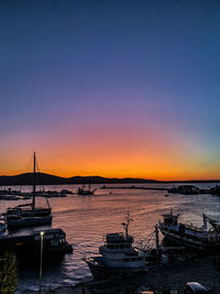 Sailboats moored in sea during sunset