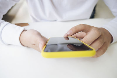 Midsection of man using mobile phone on table