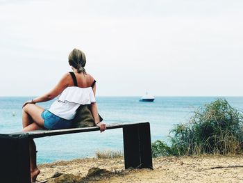 Rear view of man looking at sea against sky