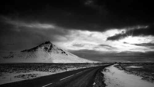 Snow covered landscape against cloudy sky