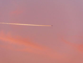 Airplane flying against vapor trail in sky