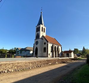 Road by building against clear blue sky