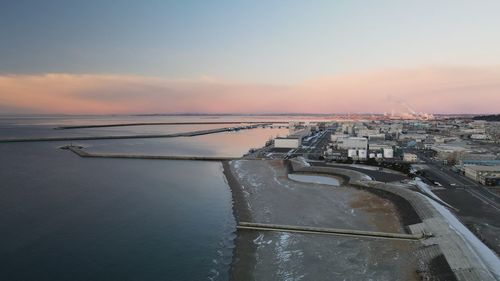 Aerial view of city at waterfront during sunset