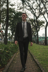 Portrait of young man standing against trees