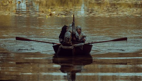 People sitting on wooden boat in lake