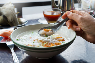 Cropped hand of woman holding spoon over soup at restaurant